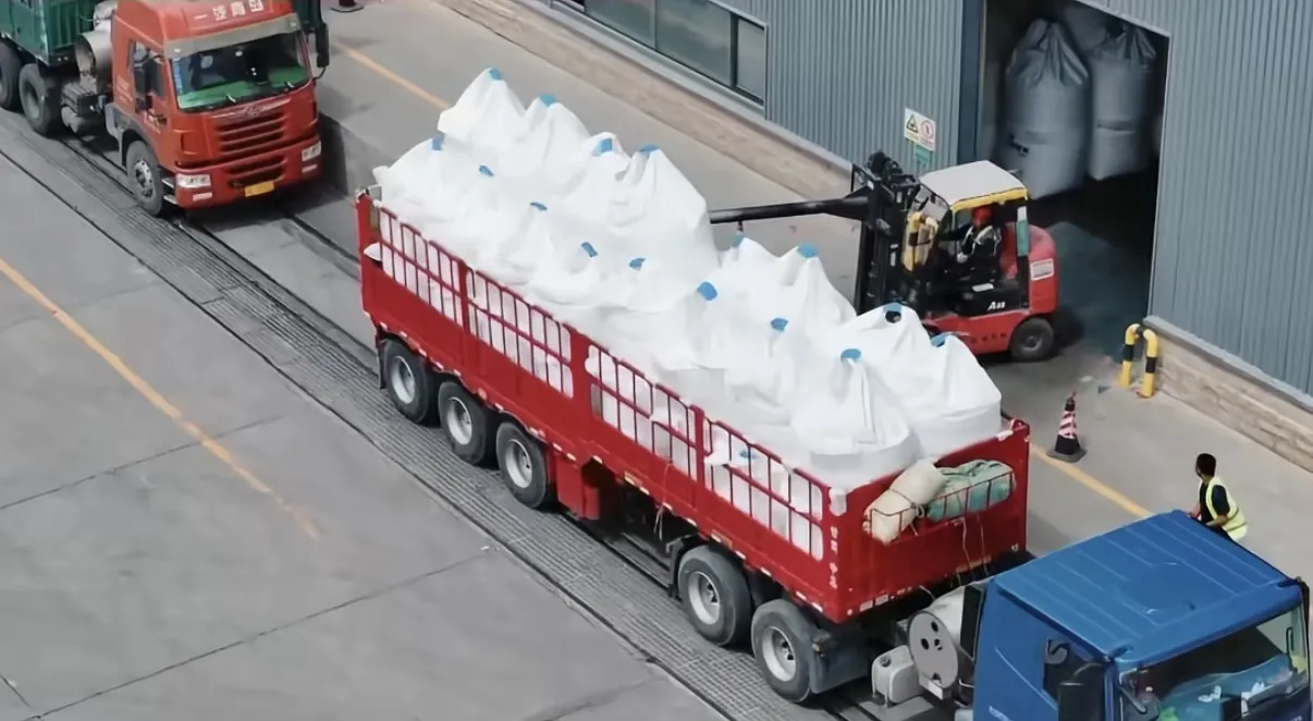 Forklift loading jumbo bags of sodium bicarbonate onto a flatbed truck at the warehouse dispatch door
